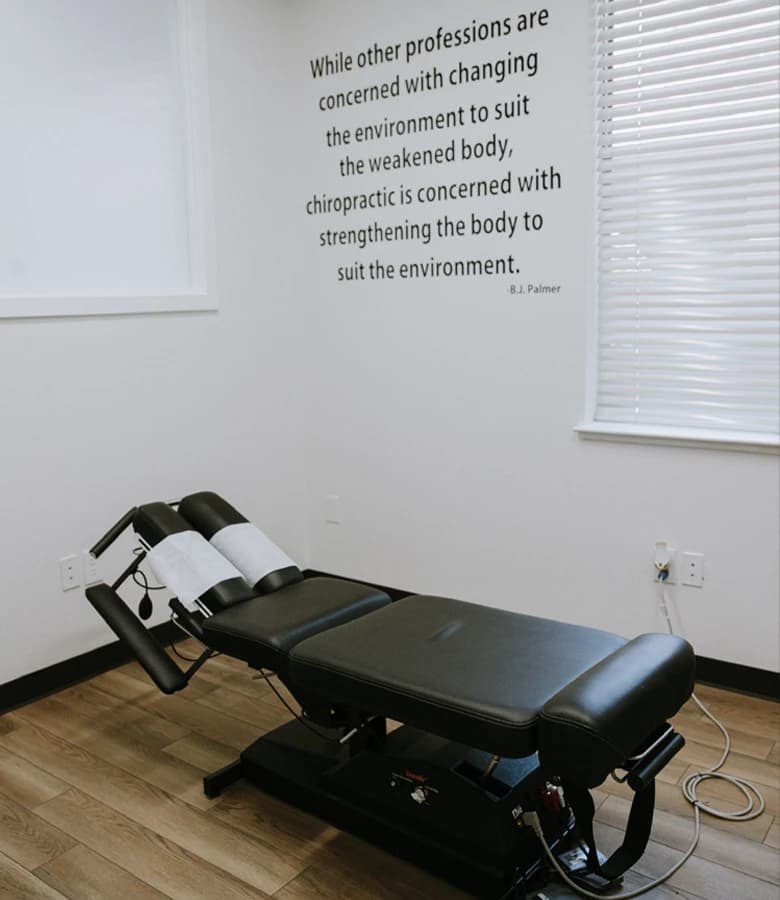 An adjusting table in the treatment room, a B.J. Palmer quote painted on the wall