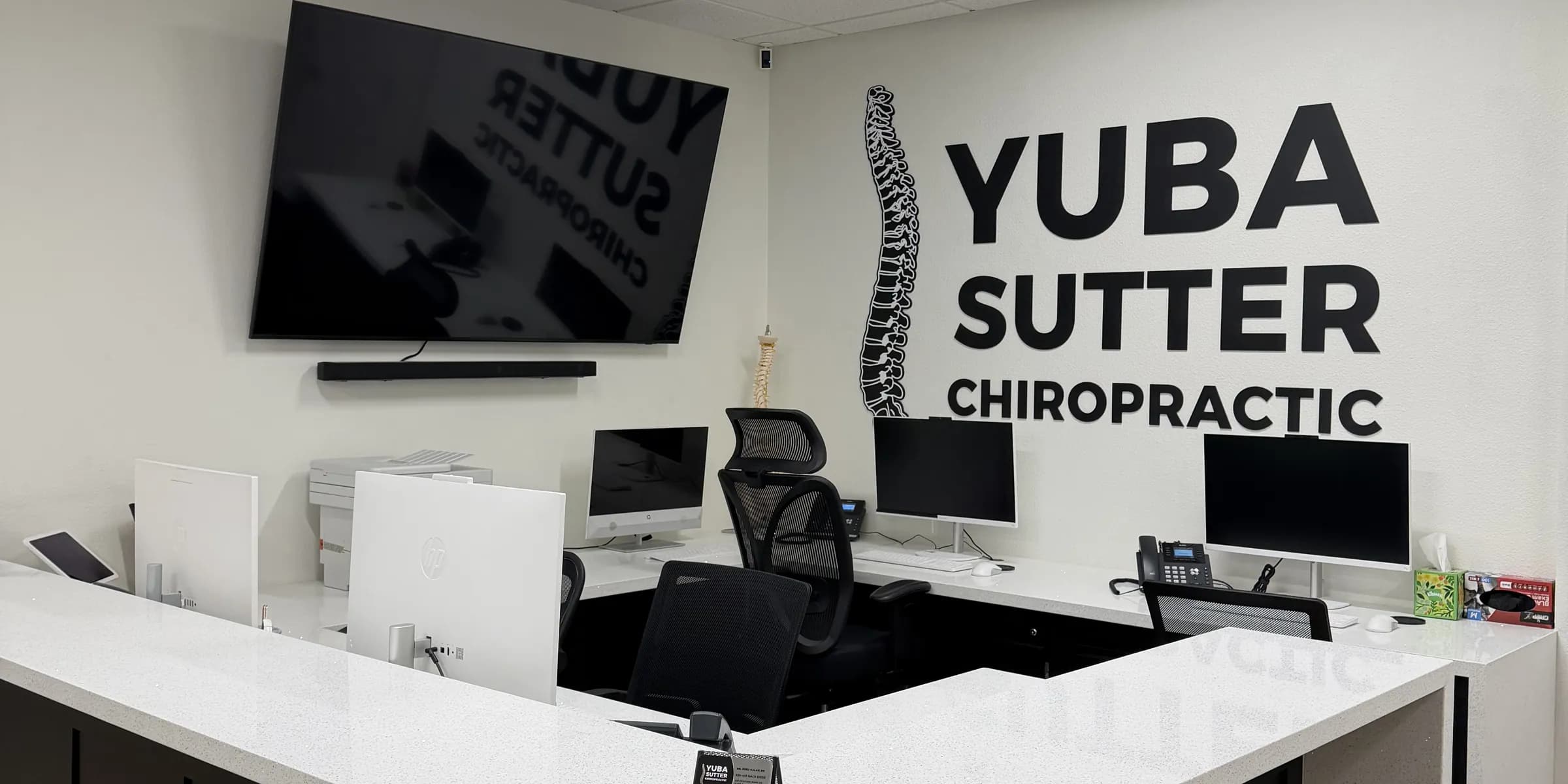 The reception desk at Yuba Sutter Chiropractic, the clinic's logo on the wall behind it