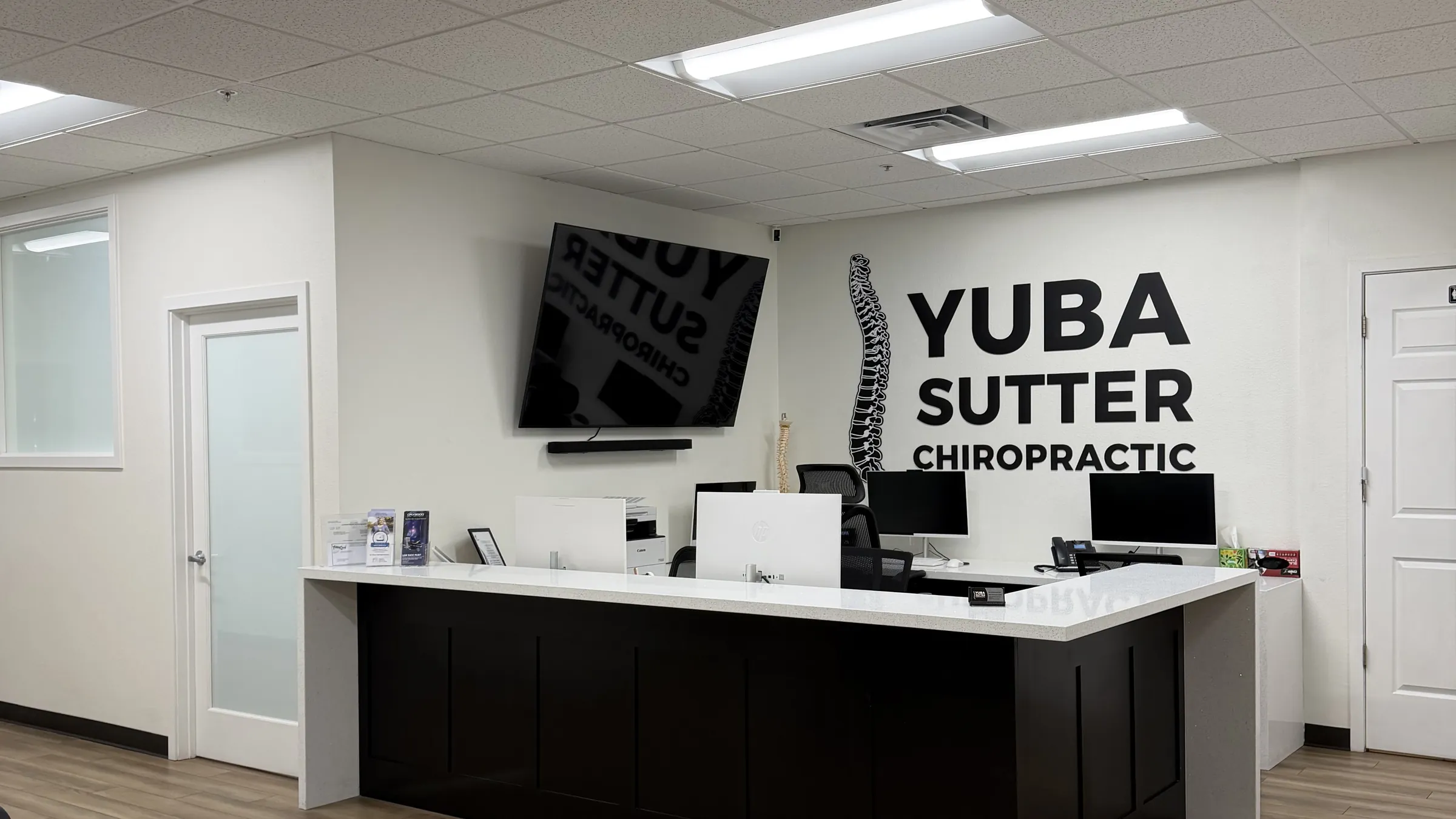 The front desk at Yuba Sutter Chiropractic, the clinic’s logo on the wall behind it