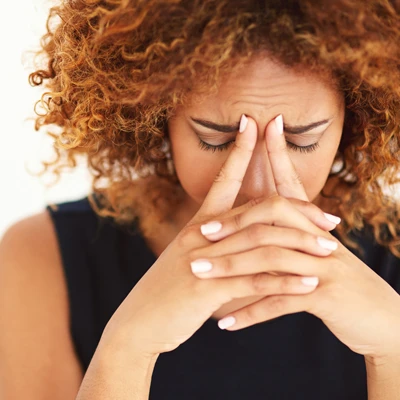A woman with head pain pinching the bridge of her nose