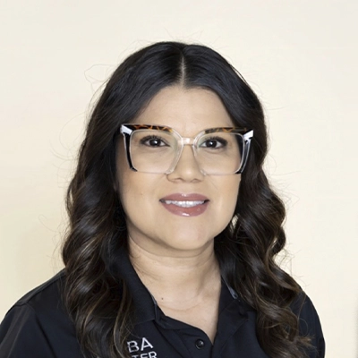 A headshot photo of Angelica wearing glasses and a black clinic polo shirt against a light background.