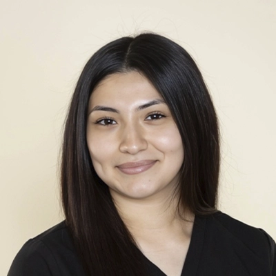 A headshot of Natalie wearing a black clinic polo shirt against a light background.